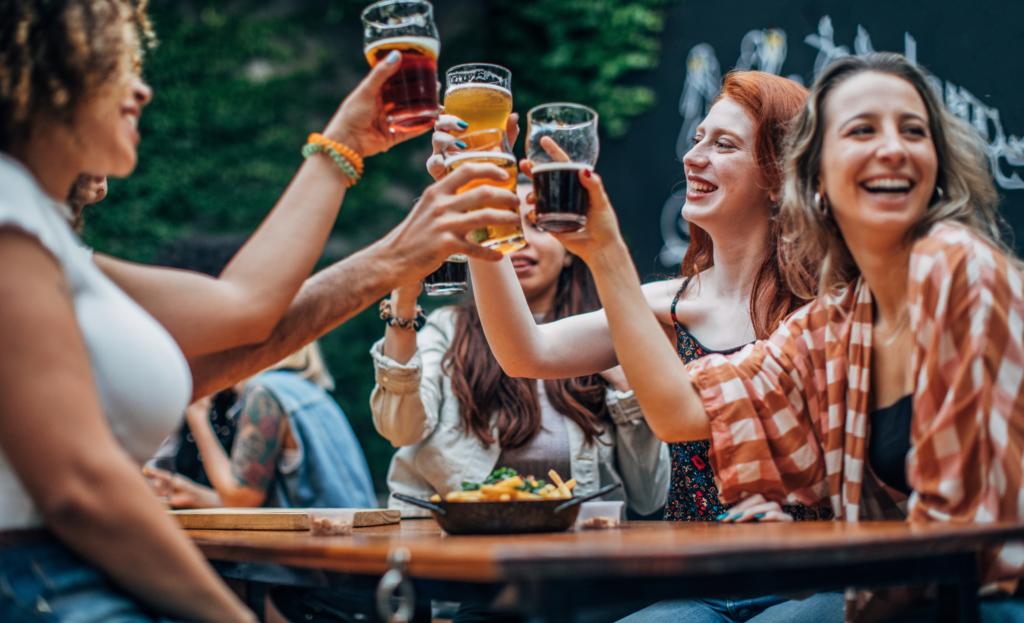 mulheres brindando sorridentes com cervejas diversas em mãos, celebrando